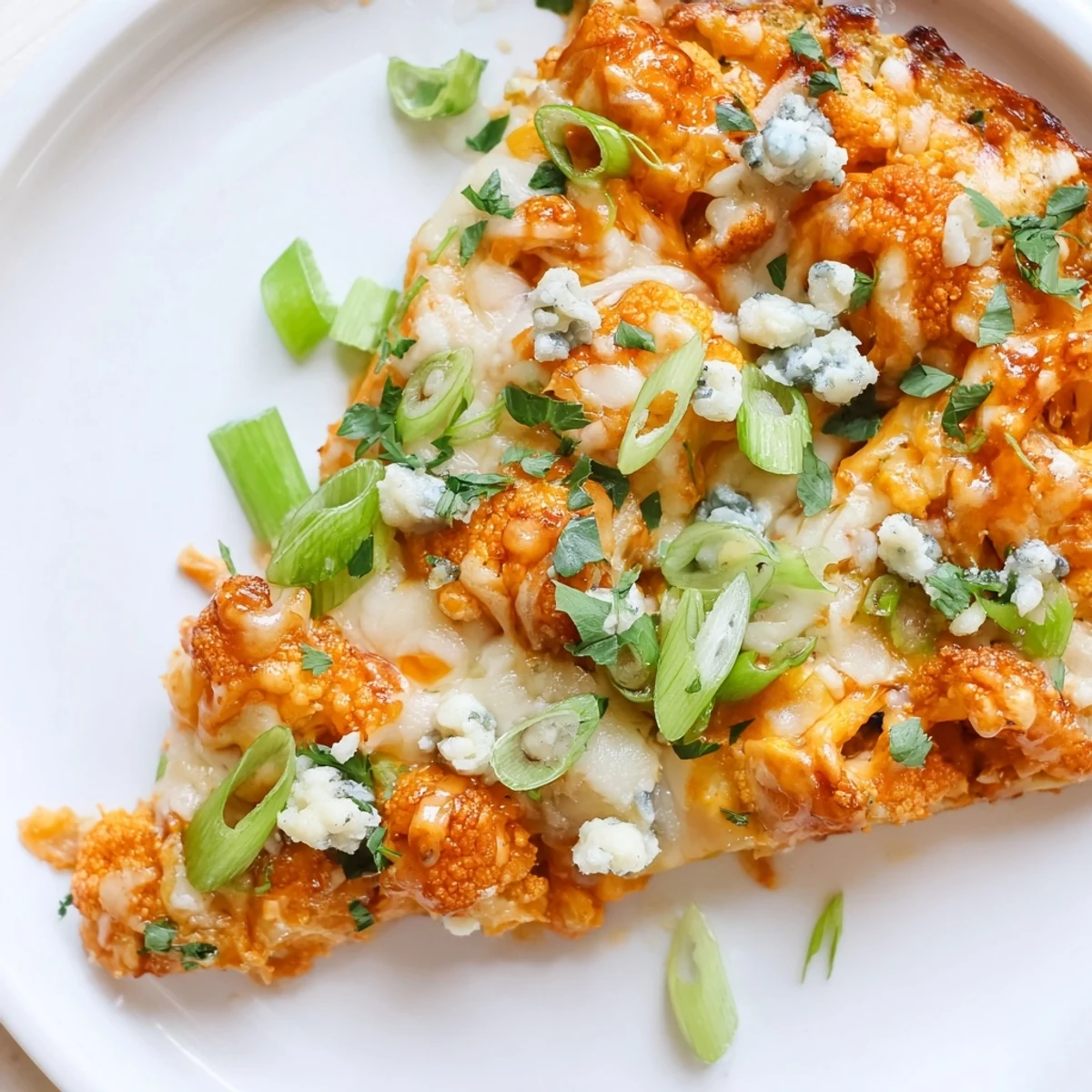 Golden-brown Buffalo Cauliflower Pizza with melted mozzarella, spicy red sauce, and fresh green onions on a crispy gluten-free crust.