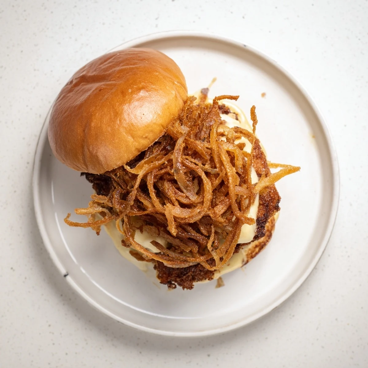 Homemade Crispy Onion Chicken Sandwich served with pickles and golden fried onions on a rustic plate.