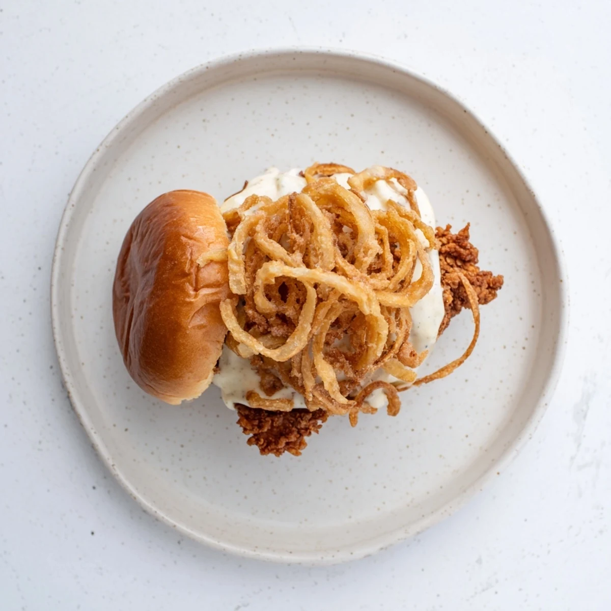 Close-up of a juicy Crispy Onion Chicken Sandwich with melted butter on toasted buns and fresh lettuce.
