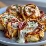 Freshly baked Tortilla Pizza Rolls arranged on a wooden board show melted mozzarella and pepperoni inside.