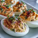 Freshly piped Million Dollar Deviled Eggs with creamy yolks and finely chopped chives topping.