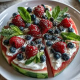 Brightly decorated 4th of July Watermelon Pizza with creamy topping, ready for slicing.