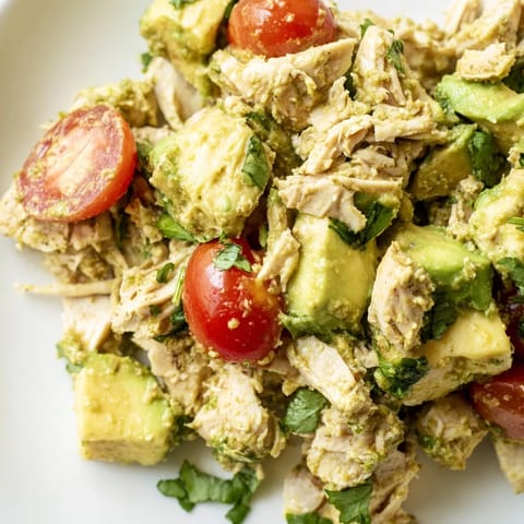 Avocado Chicken Salad served in a rustic bowl, garnished with cilantro and lime wedges.  