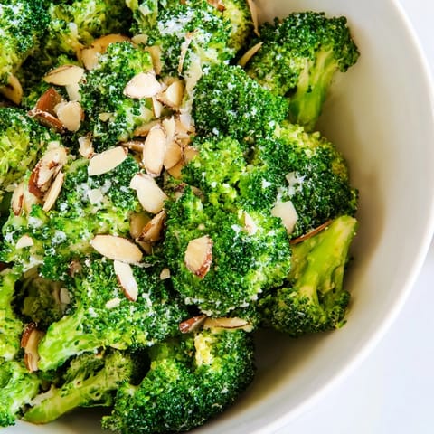 Blanched bright-green broccoli mixed with tangy dressing and crunchy almonds, served chilled as a colorful vegetarian salad.  
