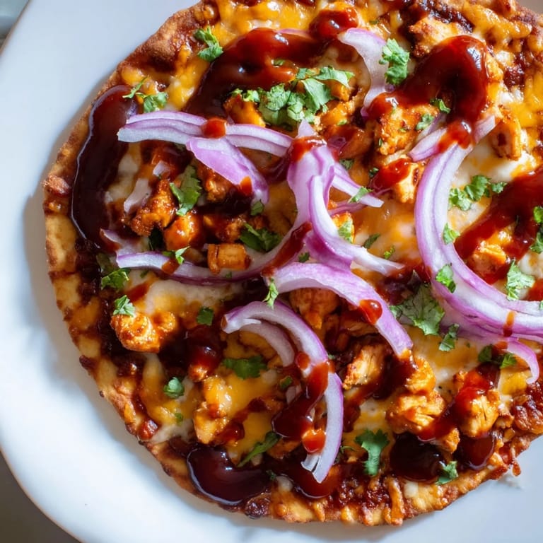 Savory BBQ chicken flatbread, featuring golden bubbly cheese and a drizzle of extra barbecue sauce.