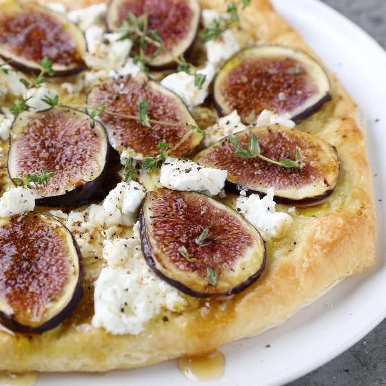 Crispy puff pastry truffle pizza featuring sweet figs, honey, and creamy goat cheese, ready to serve.