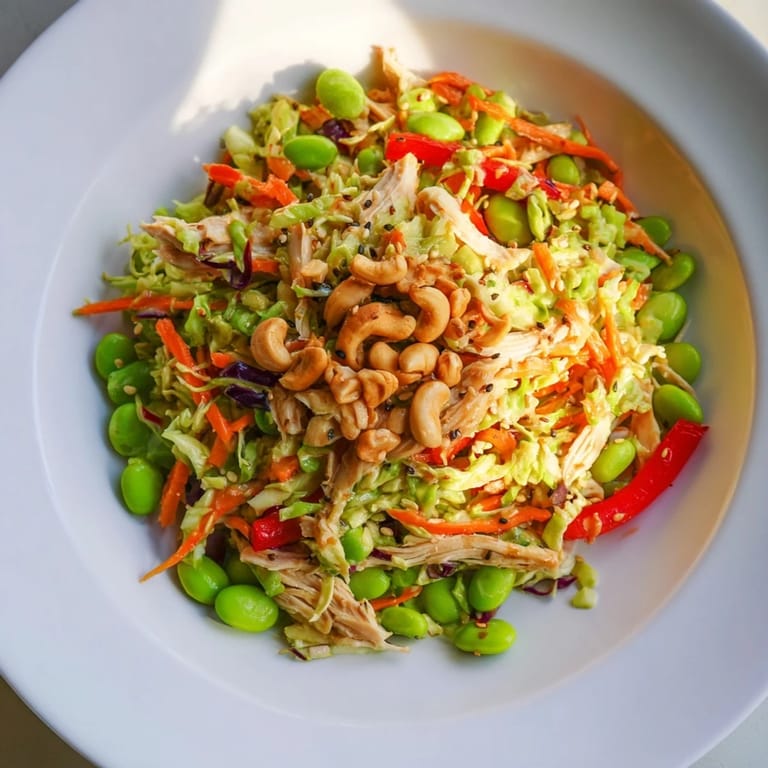 A close-up of Edamame Crunch Chicken Salad topped with toasted sesame seeds and roasted cashews, perfect for a light, refreshing lunch.
