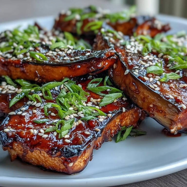 Golden roasted eggplant slices brushed with savory-sweet miso glaze, served on a rustic wooden board for a comforting vegetarian main.