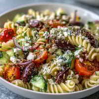 A vibrant Greek-style pasta salad with olives, feta, and fresh vegetables, perfect for summer gatherings.